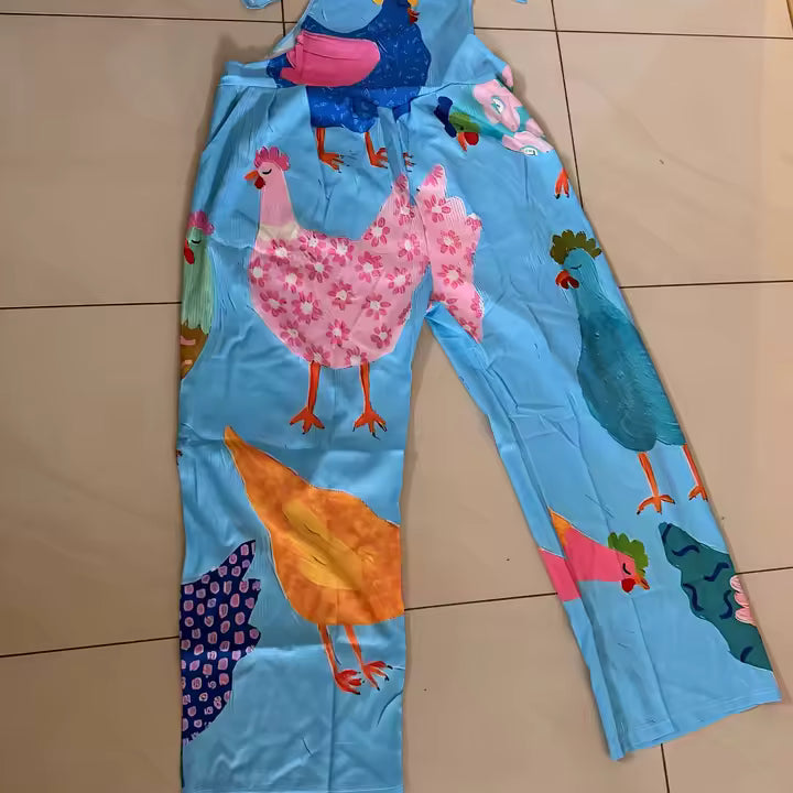 Lichtblauwe tuinbroek met opgenaaide hanenappliqués, plat gefotografeerd